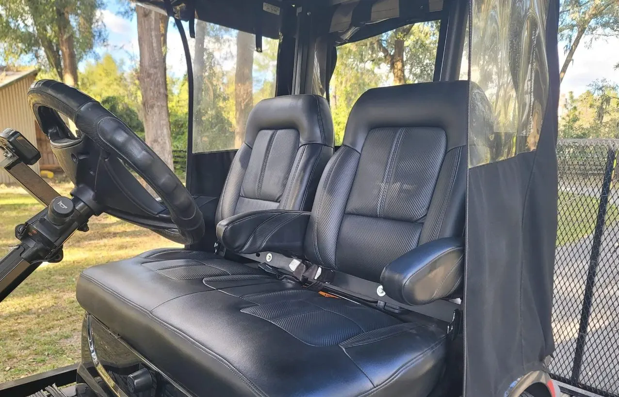 Black leather seats and steering wheel inside vehicle with forest background visible through windows