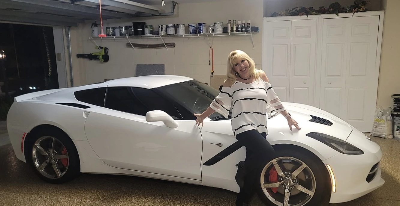 Woman posing next to white sports car in garage